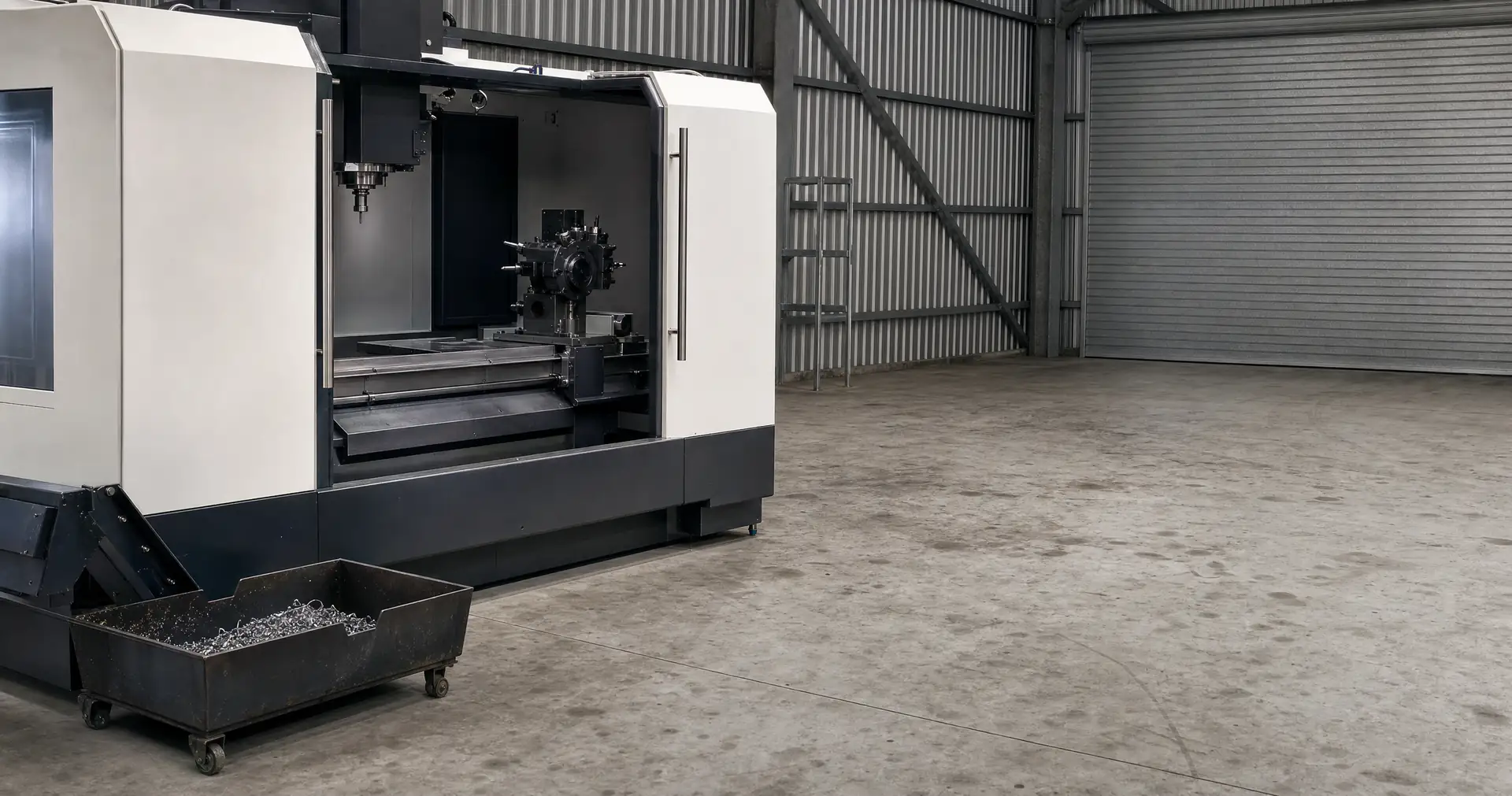 An enclosed CNC machining centre with its guard door open on a workshop floor