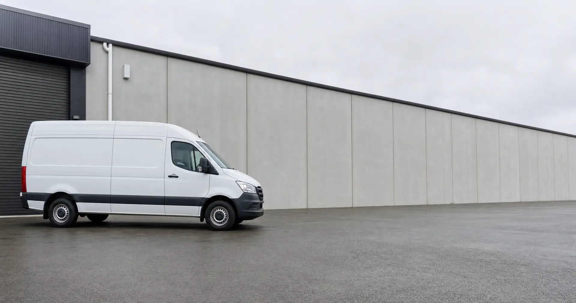 A plain white high-roof panel van parked on the forecourt of a light-industrial unit