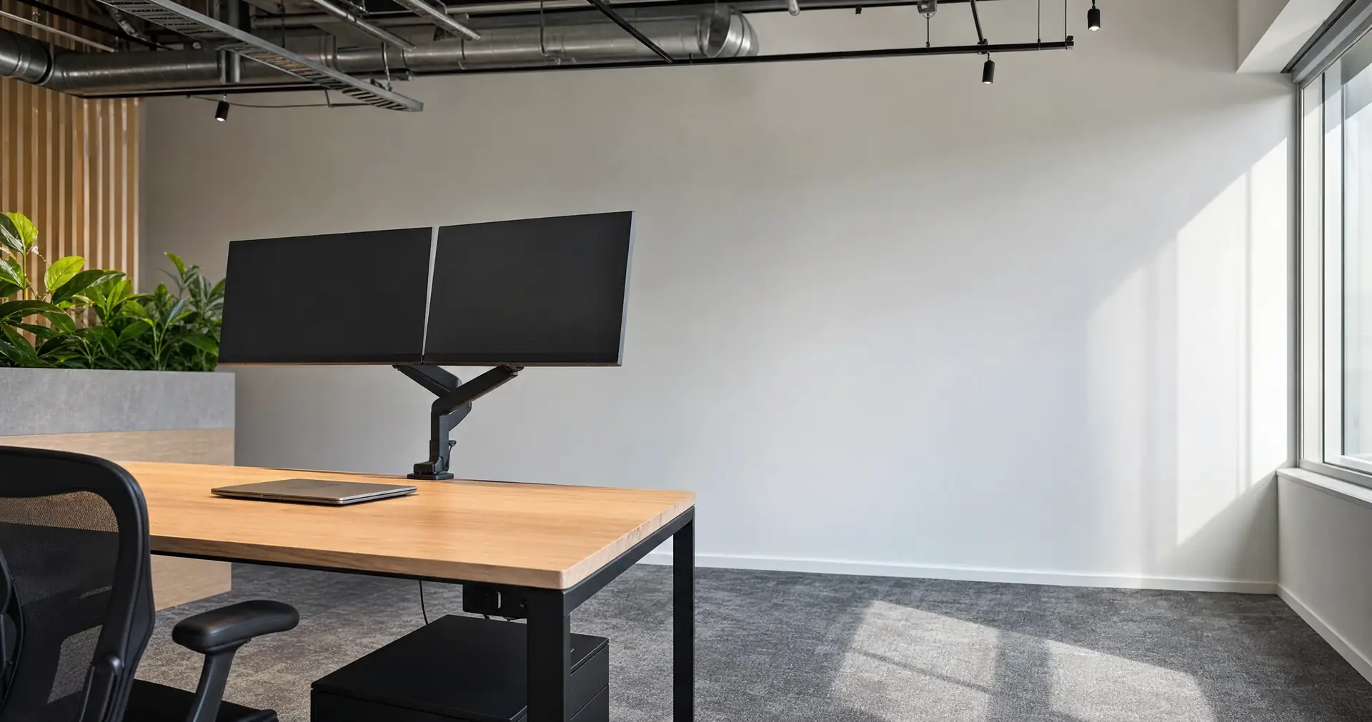 Two monitors on adjustable arms above a clear desk in a small modern office