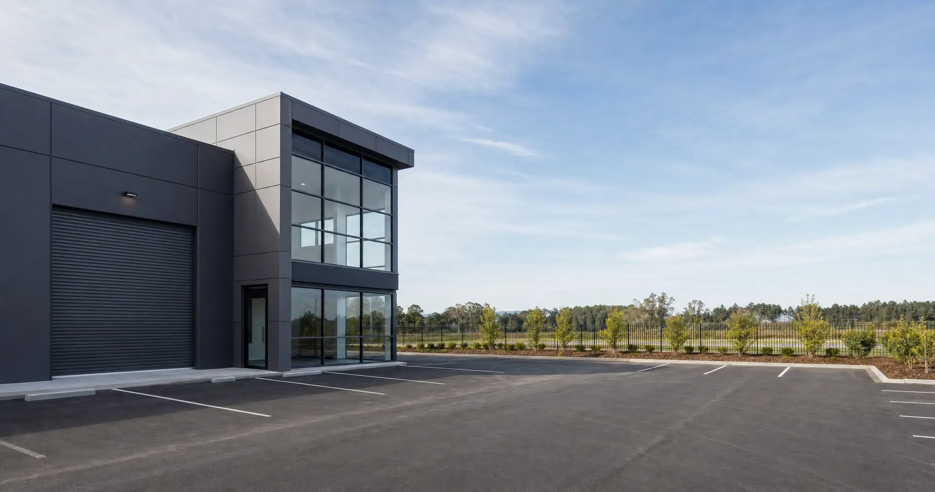 A modern tilt-slab commercial unit with a roller door and glazed office corner